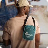 Man wearing a beige cap and light brown shirt with a green Universal Orlando bag over his shoulder - click to shop Universal Orlando merch now!