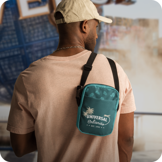 Man wearing a beige cap and light brown shirt with a green Universal Orlando bag over his shoulder - click to shop Universal Orlando merch now!