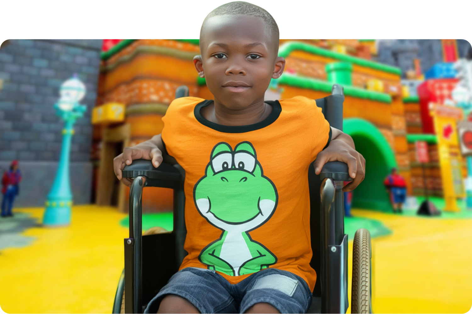 Child in a wheelchair wearing an orange shirt with a green character design, sitting in front of a colorful playground - - click to see more details about SUPER NINTENDO WORLD™ Kids Merch now!